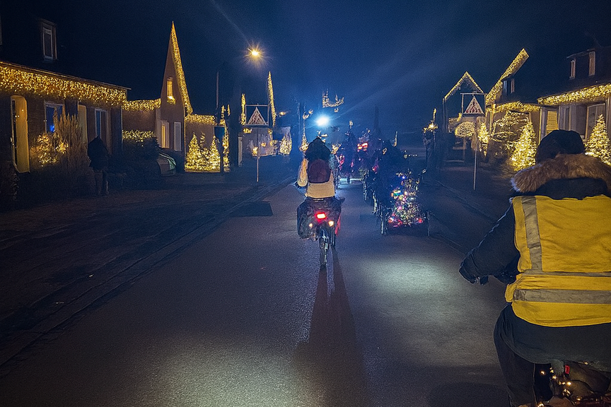 Radfahrende von hinten fotografiert, im Dunkel auf einer weihnachtlich geschmückten Straße