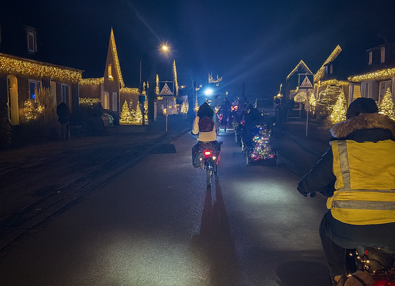 Radfahrende von hinten fotografiert, im Dunkel auf einer weihnachtlich geschmückten Straße